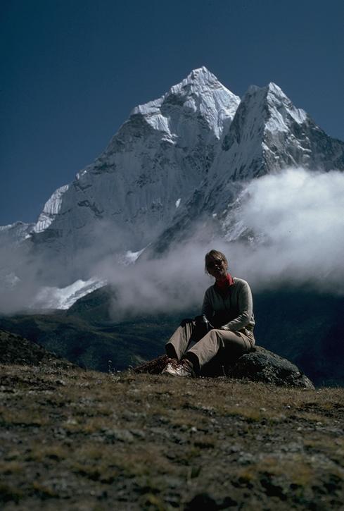 Tourist relaxing on the ridge between Pheriche and Dingboche, with the western wing of Ama Dablam rising behind